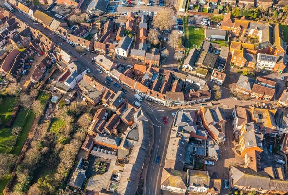 An aerial view of a residential area in a town in the UK, with a road surrounded by houses.