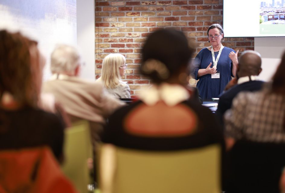 Woman giving a presentation at an RSPH event with two projectors in shot.