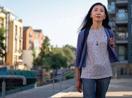An elderly Asian woman walks down a street