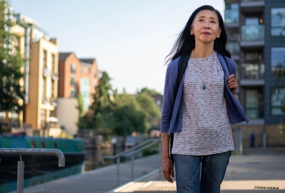 An elderly Asian woman walks down a street