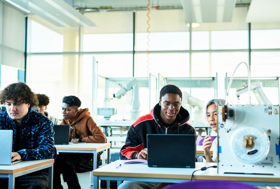A room of students studying in a bright classroom.