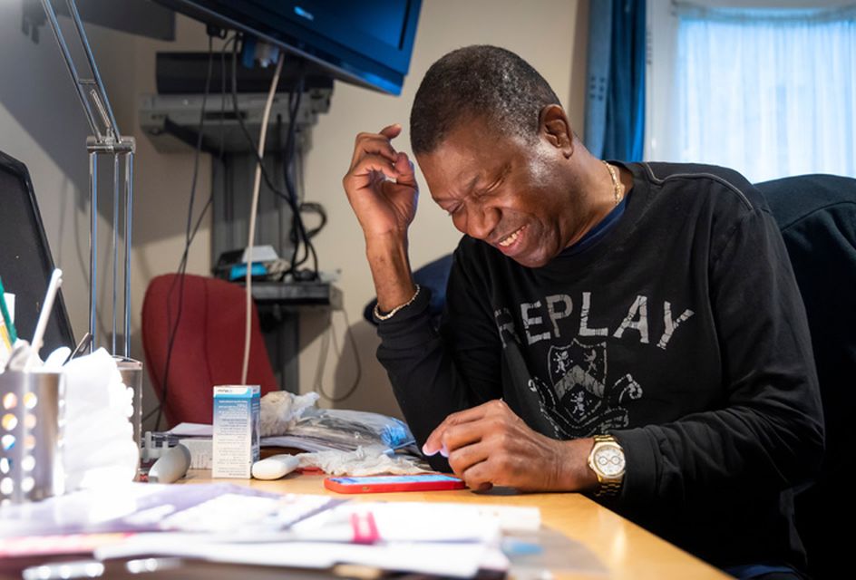 Smiling man sat a desk with papers sprawled across the desk studying for an exam.