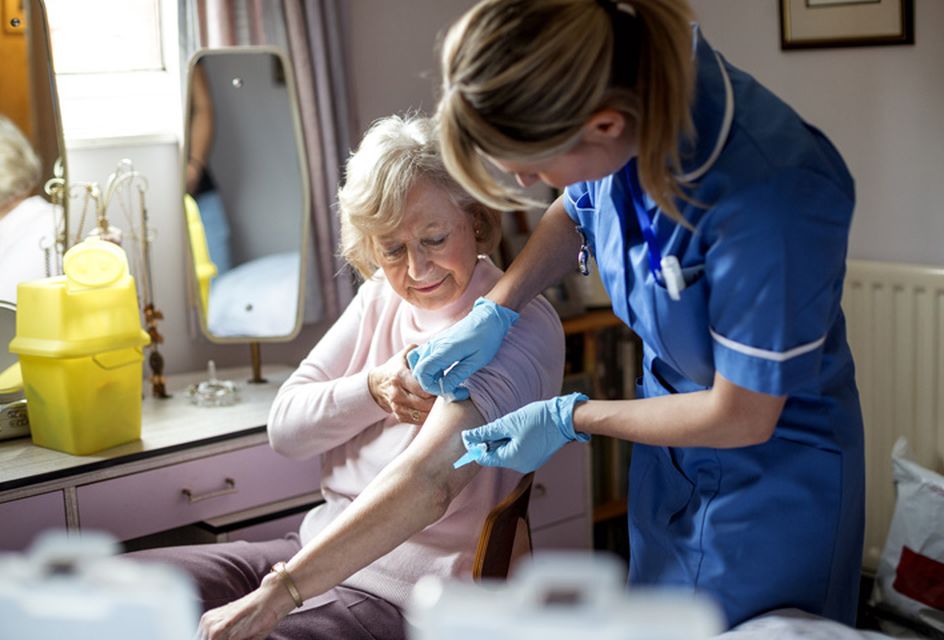 A nurse places a plaster over an elderly woman's arm.