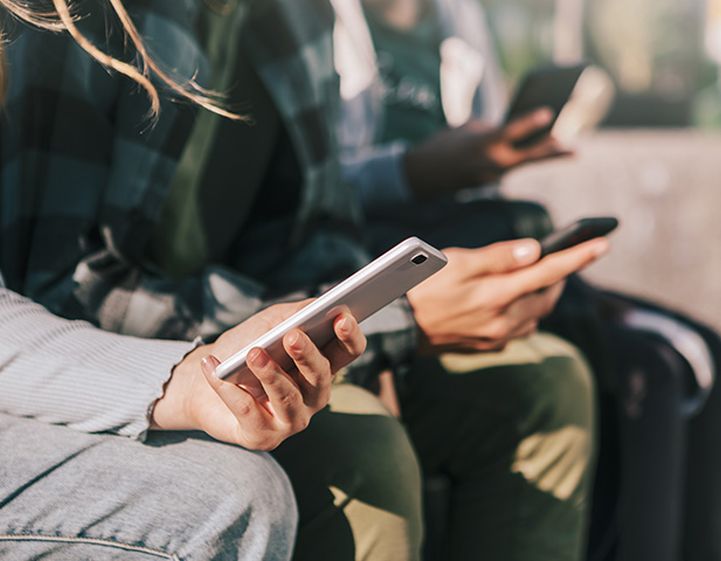 A row of teenagers holding mobile phones