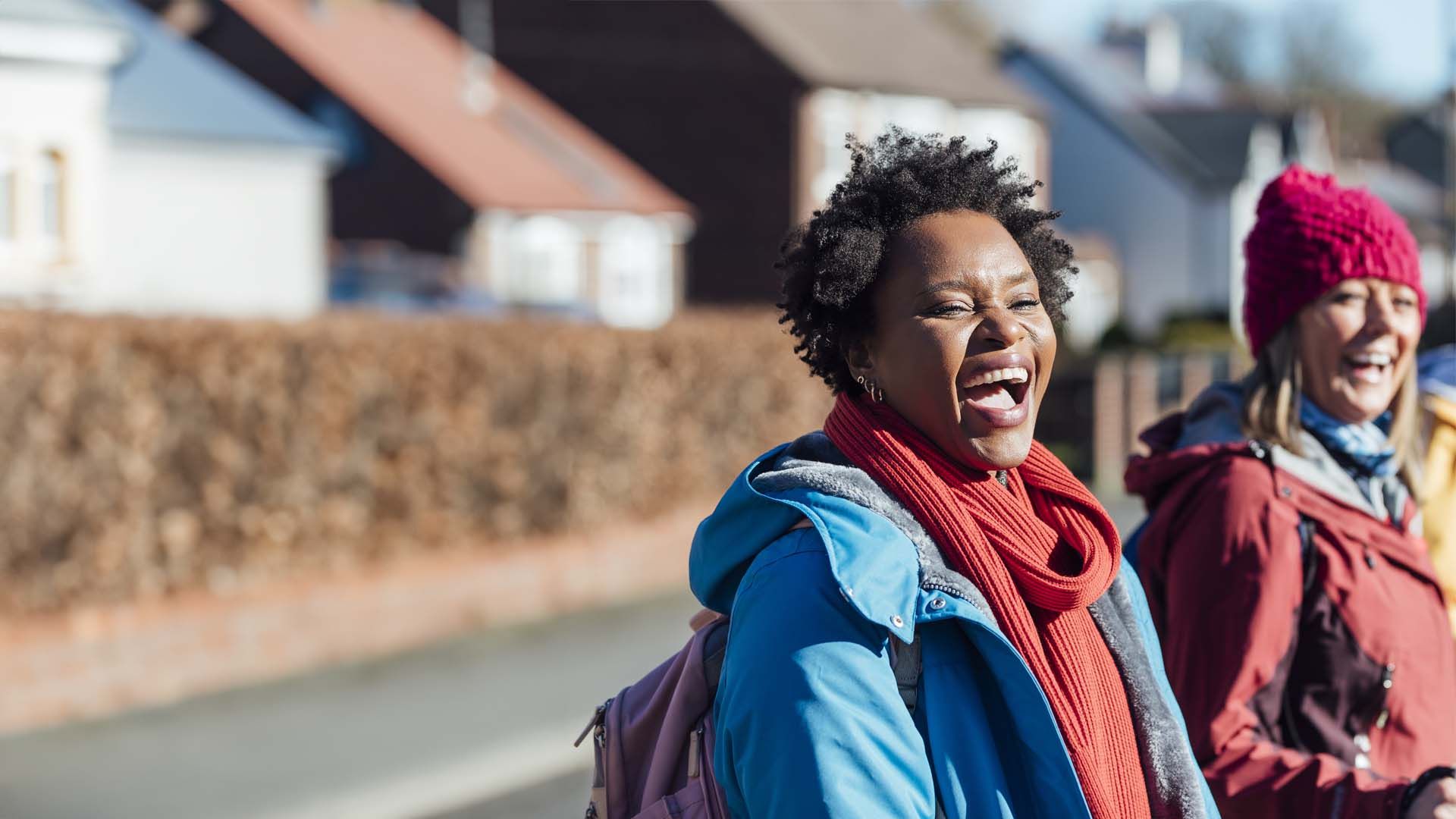 A black woman with short black hair laughing with two friends in the background.