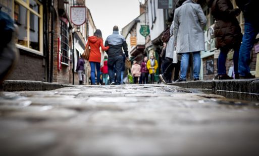 Busy pedestrian shopping street with cobblestone pavement in historic city centre on a cloudy day