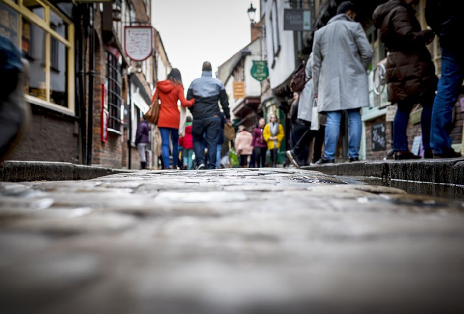 Busy pedestrian shopping street with cobblestone pavement in historic city centre on a cloudy day