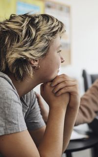 A counsellor wearing a lanyard talks to a young woman.