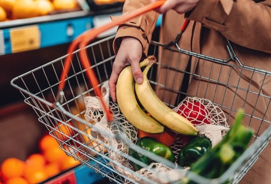 A basket of food in a supermarket, containing bananas, peppers and courgettes