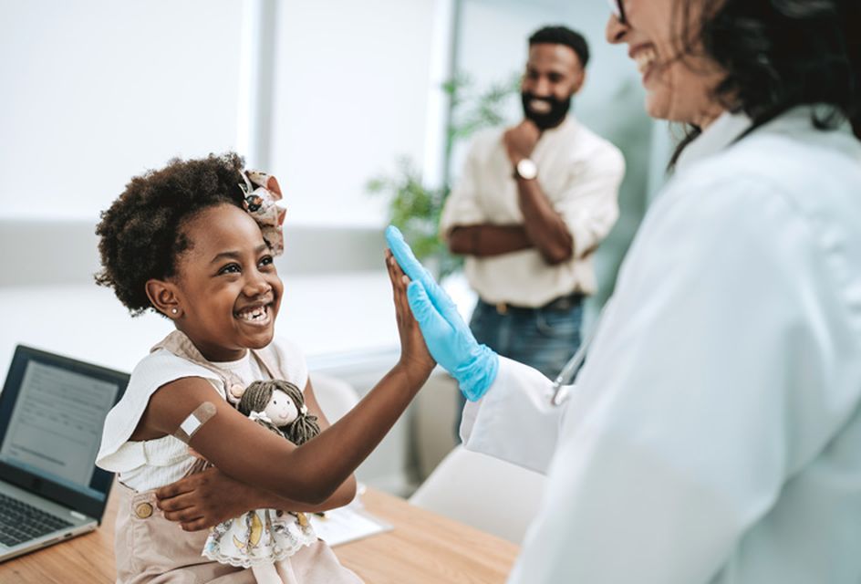 A young child high-fiving a doctor after receiving a vaccination