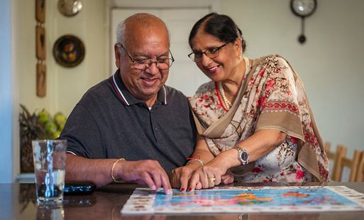 A couple smile while completing a puzzle together