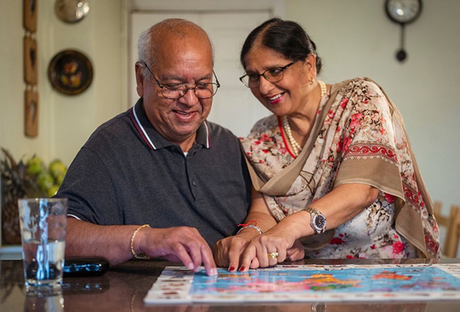 A couple smile while completing a puzzle together