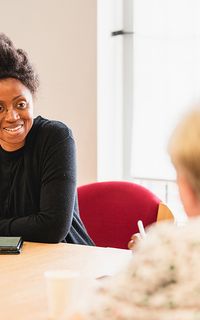 A black woman speaks to an older white woman.